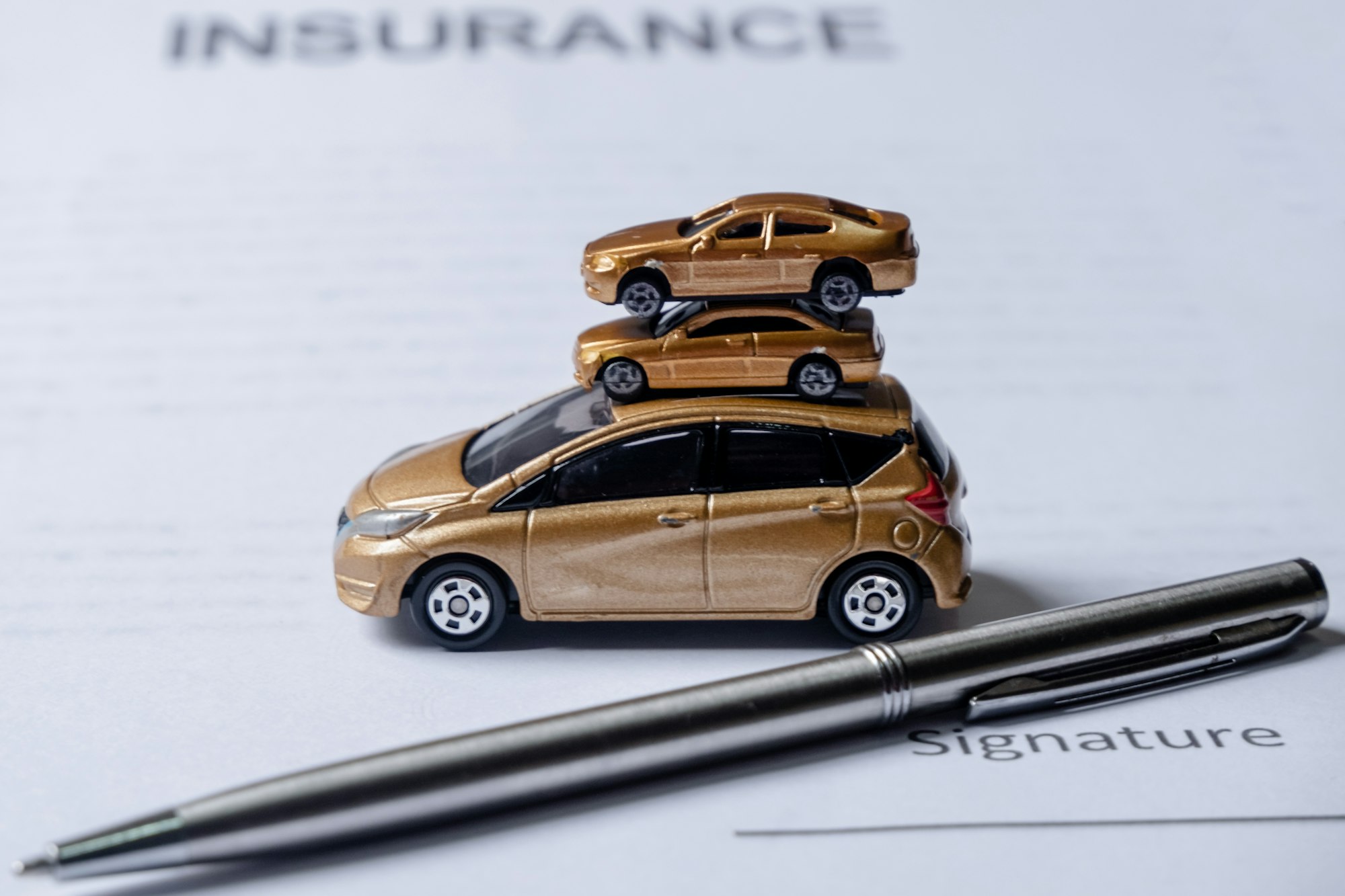 Car and pen on insurance documents. Car insurance concept.