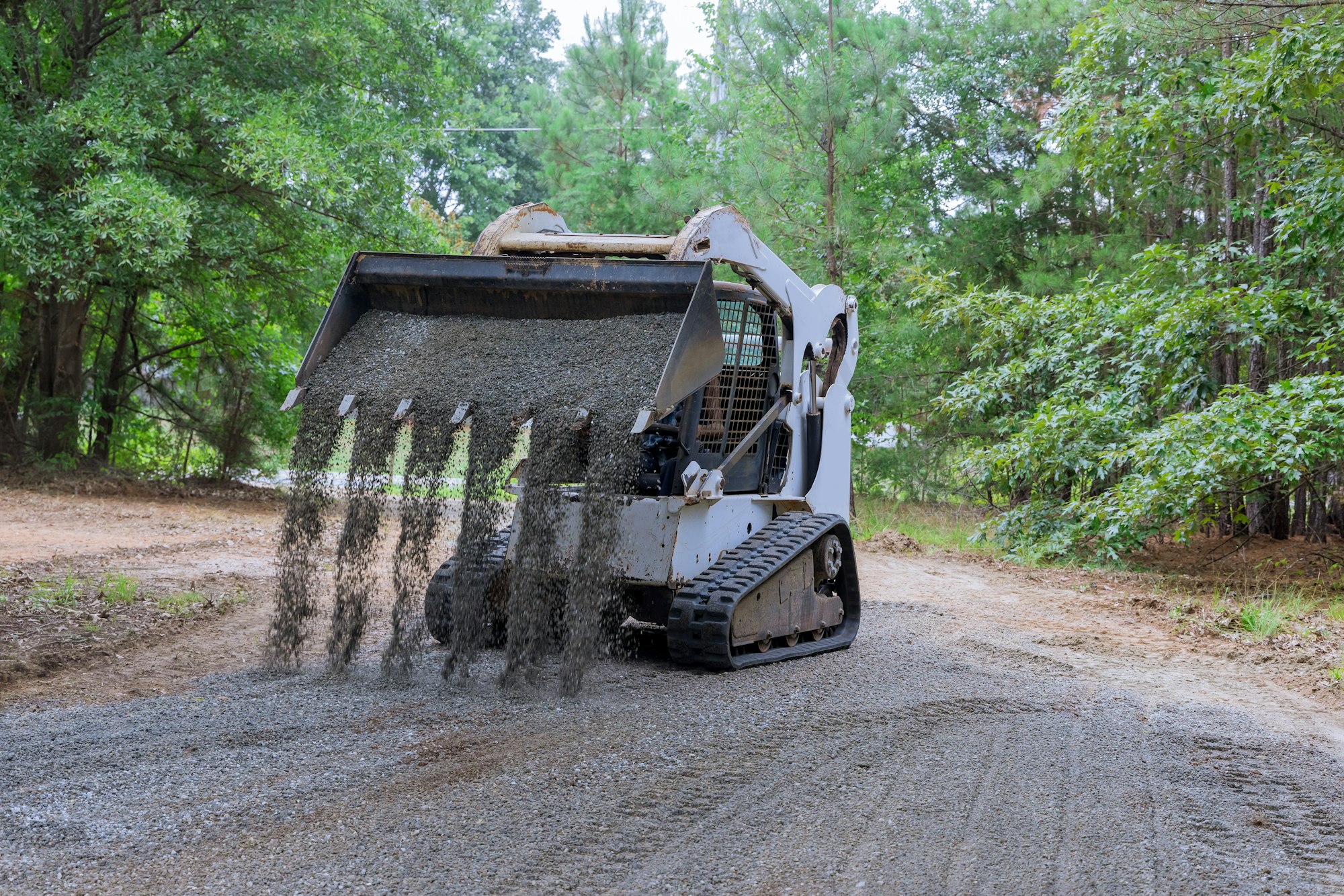 The Bobcat tractor moves and unloads gravel on the old road reconstruction site